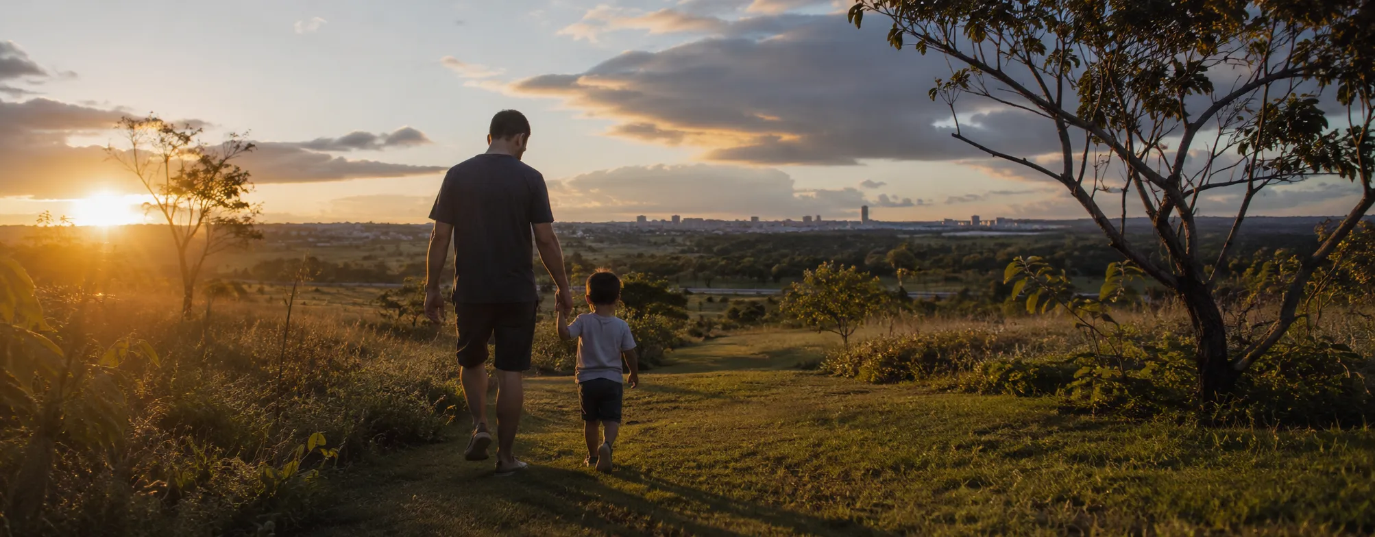 Pai e filho caminhando juntos no cerrado ao pôr do sol