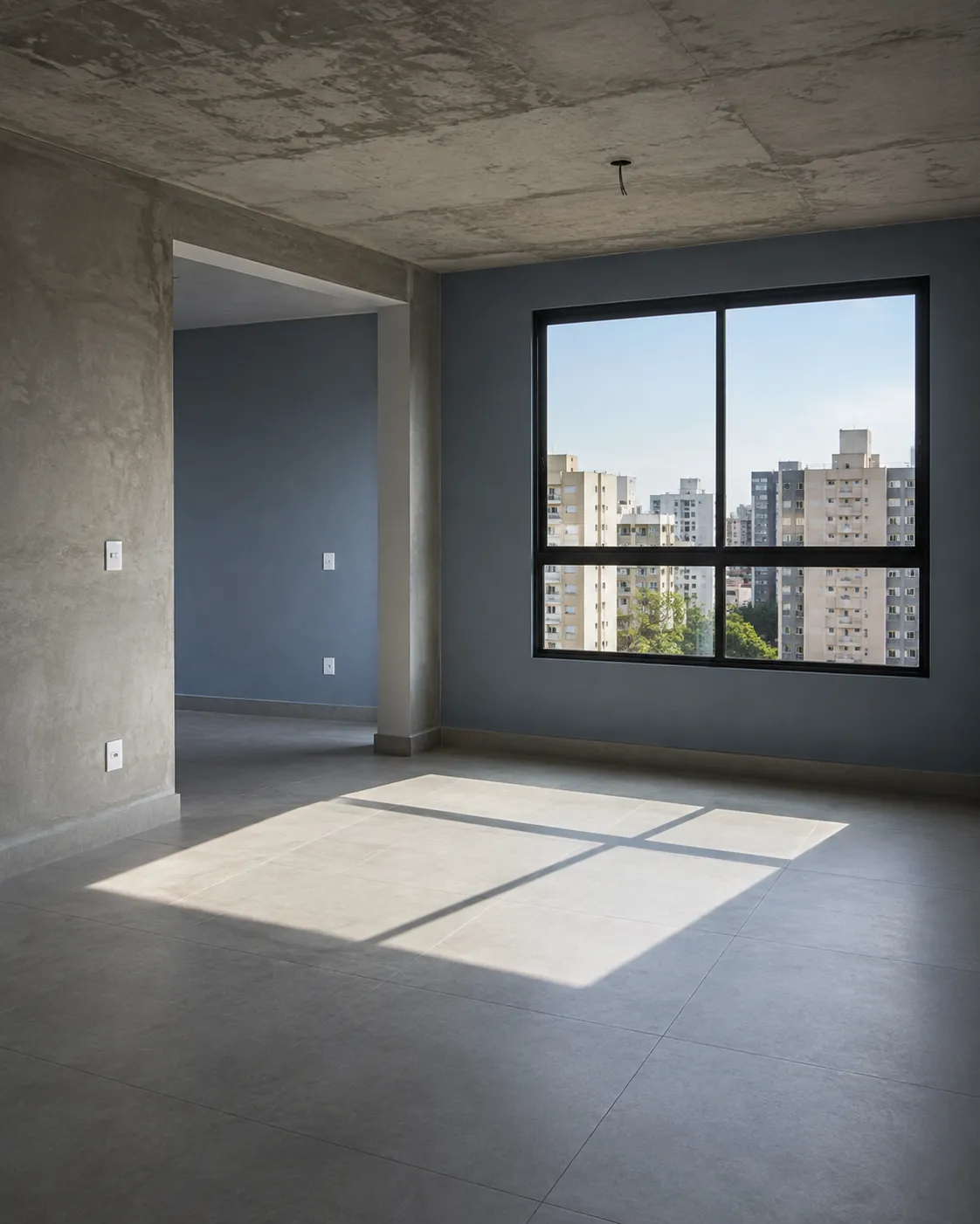 Sala de um apartamento recém-entregue, com a luz da janela no piso